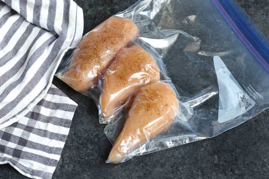 Selle al vacío las pechugas de pollo sazonadas en una bolsa ziploc en una sola capa.