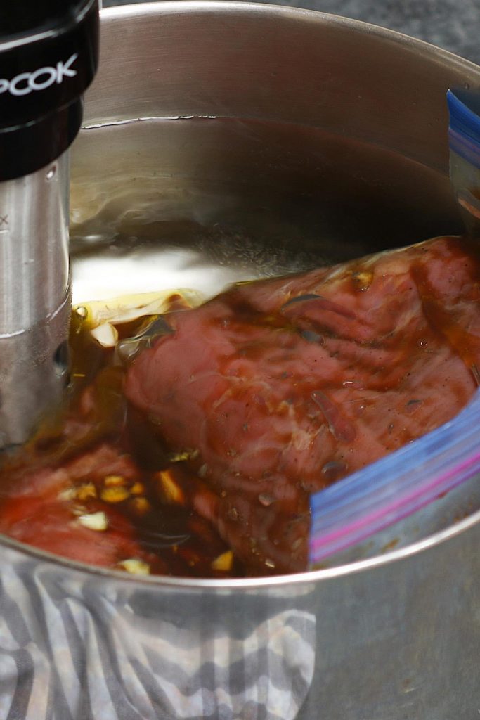 Sous vide cocinar bistec marinado en un baño de agua tibia.