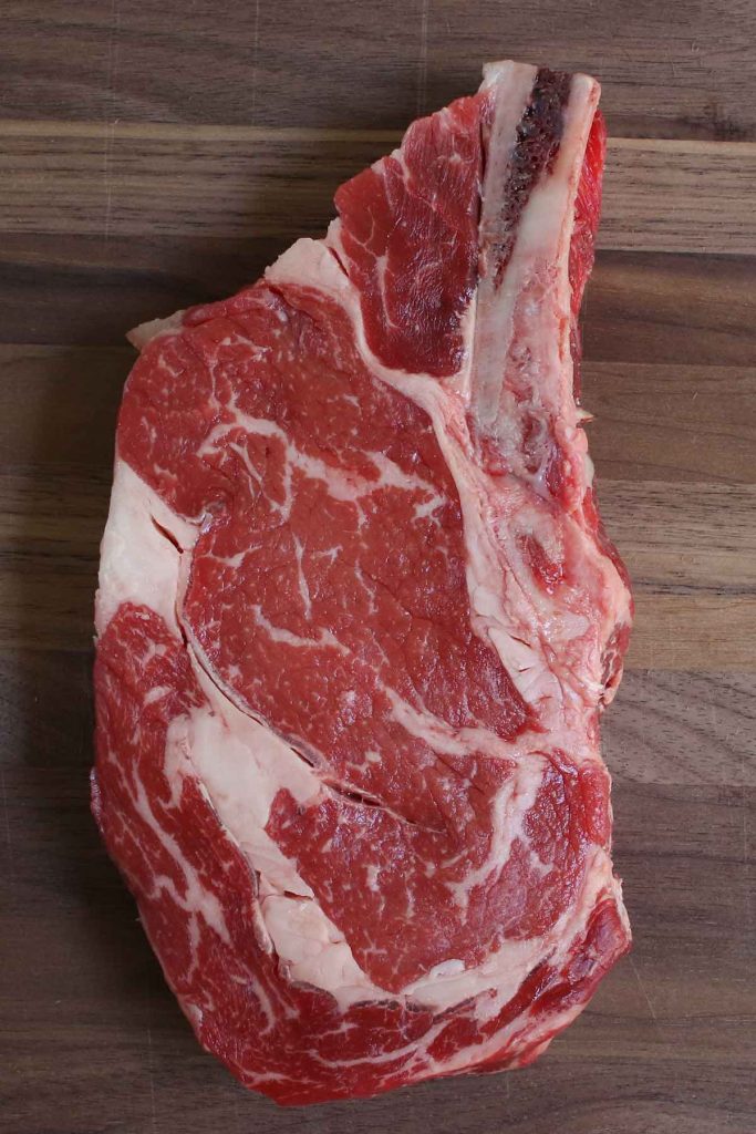 Bistec ribeye crudo en una tabla para cortar.